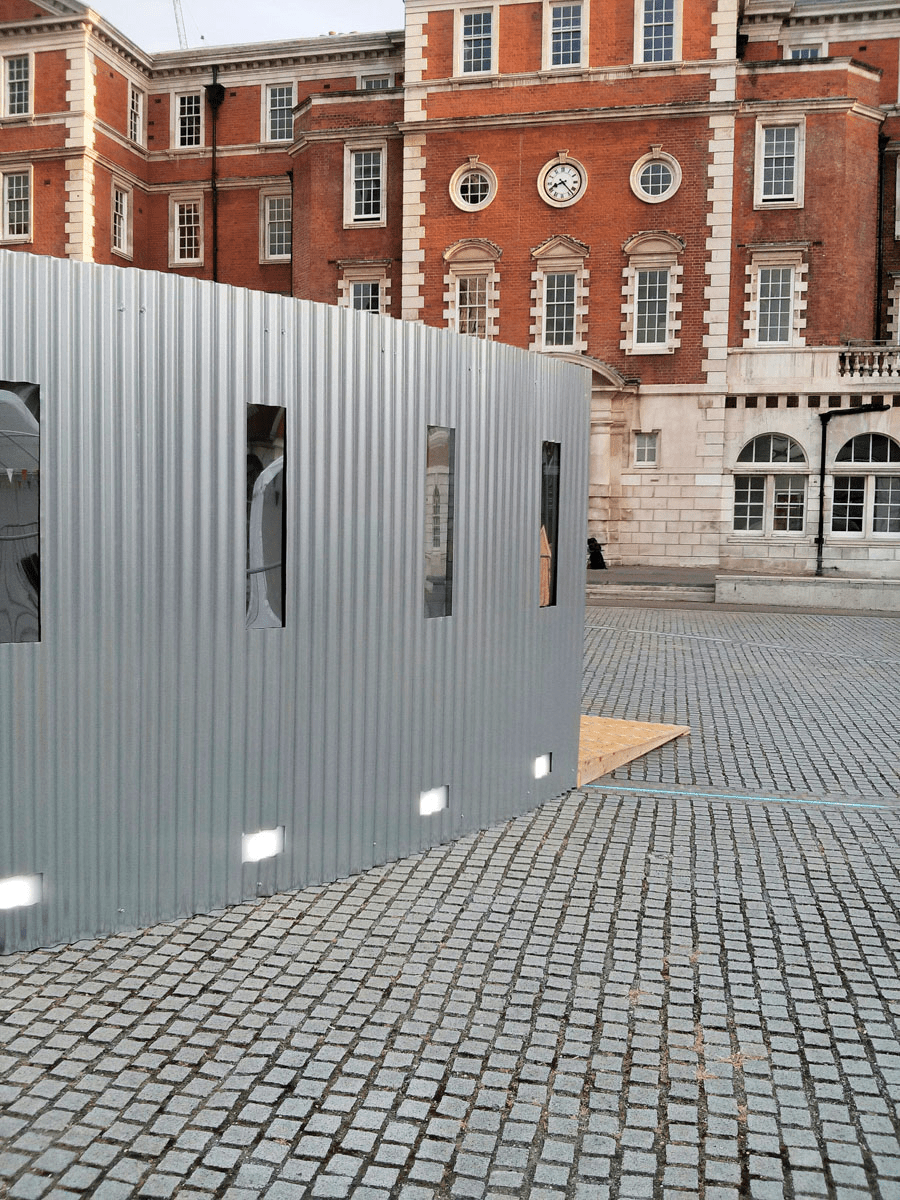 Anta Germane large scale public architectural artwork Interactive Tunnel showing curved shape and mirrored windows. Constructed from corrugated steel sheets, timber, one way persepx mirrors, PIR sensors and lights, situated in London Rootstein Hopkins Parade Ground.