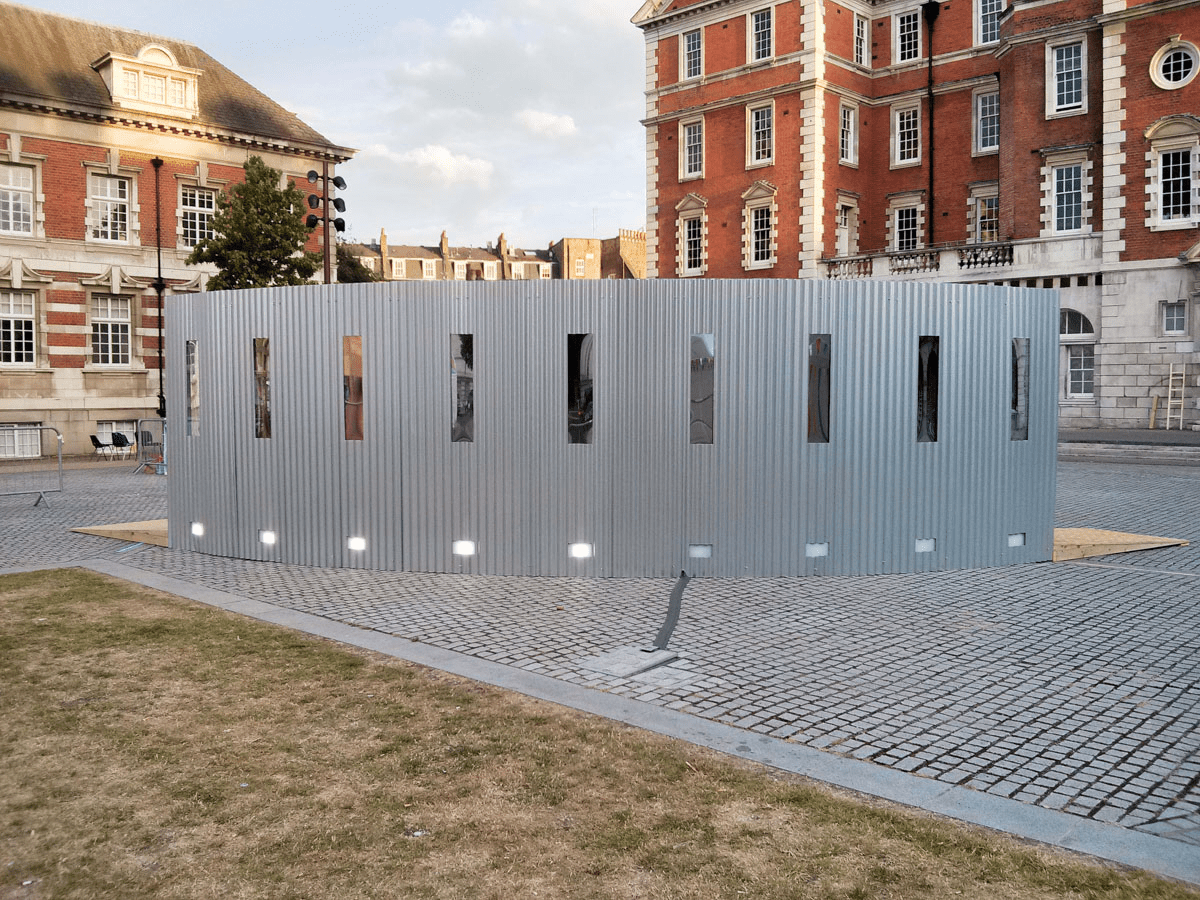 Anta Germane large scale public architectural artwork Interactive Tunnel shown at full length daytime. Constructed from corrugated steel sheets, timber, one way persepx mirrors, PIR sensors and lights, situated in London Rootstein Hopkins Parade Ground.