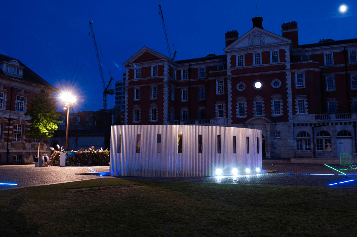 Anta Germane large scale public architectural artwork Interactive Tunnel shown at full length at night. Constructed from corrugated steel sheets, timber, one way persepx mirrors, PIR sensors and lights, situated in London Rootstein Hopkins Parade Ground.